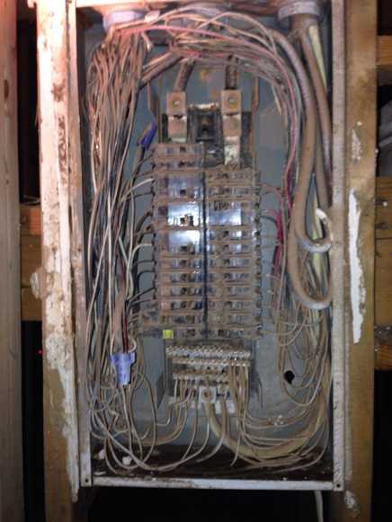 Corroded electrical panel damaged by flood water, rusted bus bars, degraded wiring, hazardous condition